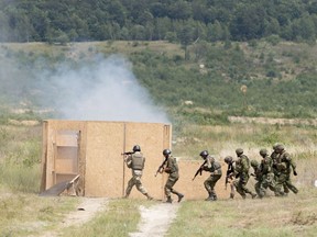 Canadian military trainers watch over Ukranian soldiers storming a building during a live fire demonstration put on for Canadian Prime Minister Justin Trudeau at the International Peacekeeping and Security Centre near Yavoriv, Ukraine Tuesday July 12, 2016.