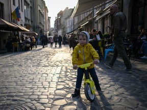 A young boy rides his balance bike through the cobbled streets in Lviv, Ukraine, on April 30, 2022.