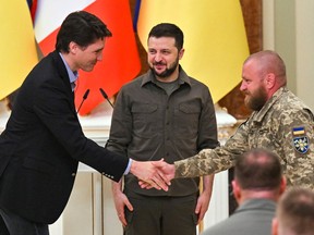 Ukrainian President Volodymyr Zelensky (C) watch' Canada's Prime Minister Justin Trudeau (L)greet an unidentified Ukrainian service man (R) as the two leaders arrive for a joint press conference in Kyiv on May 8, 2022 amid the Russian invasion of Ukraine.