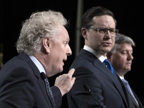 Jean Charest, left, and Pierre Poilievre, middle, spar during a Conservative leadership candidates debate in Ottawa, May 5, 2022.