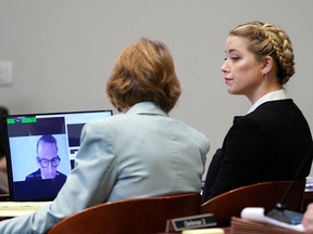 Actor Amber Heard looks on as a pre-recorded deposition testimony of attorney Adam Waldman appears on the monitor during ex-husband Johnny Depp's defamation trial against her at Fairfax County Circuit Court in Fairfax, Virginia, May 19, 2022.