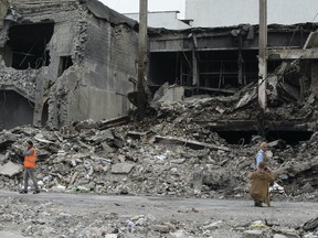 Aid workers near a refugee shelter that was destroyed by Russian bombing. Then, shortly after this photo was taken, Russian artillery exploded 200 metres away. Photo by Adam Zivo/National Post.