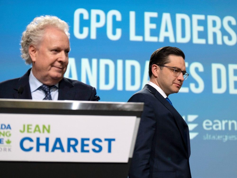 Pierre Poilievre, right, walks past Jean Charest as he takes his place on stage during the Conservative leadership debate in Ottawa, Thursday, May 5, 2022.