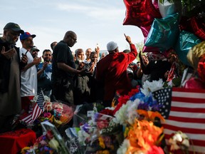 People pray at a memorial at the scene of a weekend shooting at a Tops supermarket in Buffalo, New York, U.S. May 20, 2022.  REUTERS/Lindsay DeDario