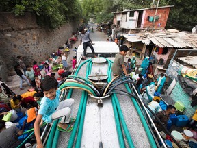 Residents use hoses to collect drinking water from a tanker truck during a hot day in New Delhi on May 3, 2022. India's Supreme Court has ruled that citizens have the right to refuse to be vaccinated, and that public health measures must be proportionate to the risk.