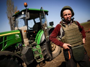 Yuri, a Ukrainian farmer, wearing body armor and helmet, works at the topsoil in a field, amid Russia's invasion of Ukraine, in Zaporizhzhia region, Ukraine April 26, 2022.