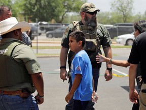 A child gets on a school bus as law enforcement personnel guard the scene of a shooting at Robb Elementary School in Uvalde, Texas, May 24, 2022.