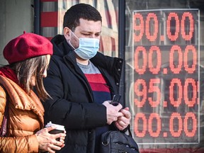 People walk past a currency exchange office in central Moscow on Feb. 28.