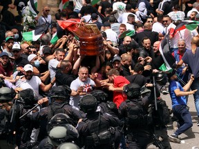 People carry the coffin of Al Jazeera reporter Shireen Abu Akleh, who was killed during an Israeli raid in Jenin in the West Bank, as funeral-goers clash with Israeli security forces, in Jerusalem, May 13, 2022.