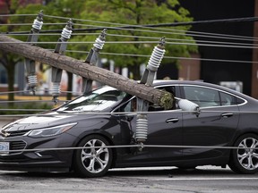 A motorist remains in their vehicle as they wait for crews to make sure they can leave safely, after power lines and utility poles came down onto their car during a major storm, on Merivale Road in Ottawa, on Saturday, May 21, 2022.&ampnbsp;Environment Minister Steven Guilbeault says emergency alerts that broadcast over the cell network to warn of severe weather should be improved to make sure they're getting to the right people at the right time.THE&ampnbsp;CANADIAN PRESS/Justin Tang