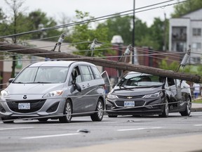 Motorists remain in their vehicles as they wait for crews to make sure they can leave safely, after power lines and utility poles came down onto the roadway during a major storm, on Merivale Road in Ottawa, on Saturday, May 21, 2022.