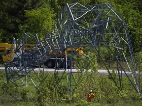 A utility worker assesses a transmission tower as they work to sever it from its base to remove it, after it was damaged in Saturday's major storm in Ottawa, on Tuesday, May 24, 2022.
