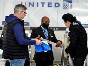 A United Airlines worker assists travelers after the Biden administration announced it would no longer enforce a COVID-19 mask mandate on public transportation, following a federal judge's ruling that the 14-month-old directive was unlawful, at Ronald Reagan Washington National Airport in Arlington, Virginia, April 19, 2022.
