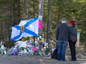 A couple pays their respects at a roadblock in Portapique, N.S. on April 22, 2020. The Mountie who led the first response to the Nova Scotia mass shooting testified Monday his plans to block the killer's escape route were thrown off by a subordinate's "misunderstanding," and a crush of competing duties.