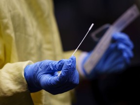 A nurse gets a swab ready to perform a test on a patient at a drive-in COVID-19 clinic in Montreal, on Wednesday, Oct. 21, 2020. Quebec is reporting 14 more deaths linked to COVID-19 and a 23-patient jump in the number of hospitalizations associated with the disease.