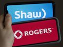 A woman holds two cellphones in this photo illustration, Monday March 29, 2021 in Chelsea, Que. The House of Commons Standing Committee on Industry, Science and Technology is hearing from Rogers and Shaw Communications executives on a merger.