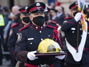 The helmet of fireman Pierre Lacroix is carried to the church for his funeral services in Montreal, Friday, Oct. 29, 2021. Quebec's chief coroner has called a public inquiry into the drowning of a Montreal firefighter last year.