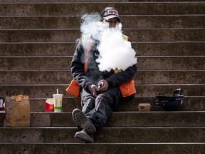 A construction worker exhales after using a vaping device while eating lunch on the steps at Robson Square, in Vancouver, on Monday, March 8, 2021. The government is in the midst of reviewing the 2018 bill that legalized vaping for the first time, and appears to be veering away from the narrow path between treating vapes as a harm reduction tool -- or a danger in and of themselves.
