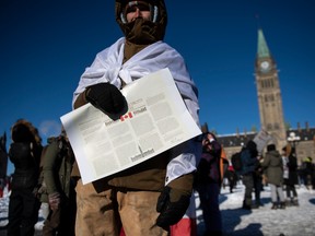 A man holds a copy of the Canadian Charter of Rights and Freedoms during a rally on Parliament Hill.