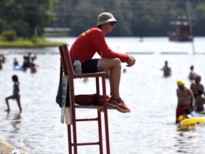 An City of Ottawa lifeguard keeps an eye on swimmers during a heatwave at Mooney's Bay Beach in Ottawa on Sunday, Aug. 16, 2015. Municipalities across Canada are grappling with lifeguard shortages as city pools and beaches open for the summer.