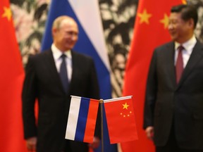 Russian and Chinese national flags are seen on a table with Russian President Vladimir Putin, left, and his Chinese counterpart Xi Jinping in the background during a signing ceremony in Beijing in 2014.