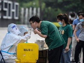 A health worker gets a swab sample from a man to be tested for Covid-19 coronavirus at a nucleic acid testing station in Beijing on June 10, 2022.