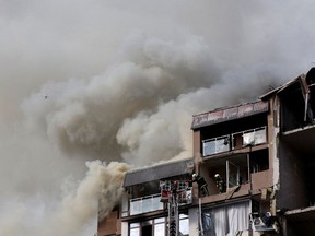 Firefighters work to put out a fire as smoke rises from residential building damaged by a Russian missile strike, as Russia's attack on Ukraine continues, in Kyiv, Ukraine June 26, 2022.