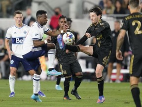 Vancouver Whitecaps forward Cristian Dájome, center left, and Los Angeles FC midfielder Ilie Sánchez (6) kick the ball during the first half of an MLS soccer match in Los Angeles, Sunday, March 20, 2022. 
