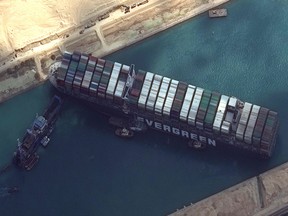 Tug boats and dredgers attempt to free the MV Ever Given in the Suez Canal, on March 26, 2021.