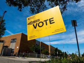 People walk by a vote sign near a polling station during Ontario?s provincial election in Hamilton, Ontario, Canada June 2, 2022.  REUTERS/Carlos Osorio