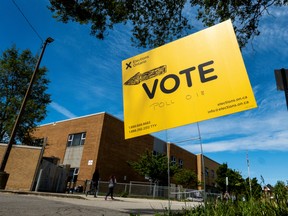 People walk by a vote sign near a polling station in Hamilton, Ont., on June 2.