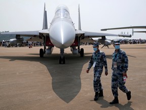 Chinese military personnel pass by the J-16D electronic warfare airplane during Airshow China 2021, in Zhuhai, China, on Sept. 29, 2021.