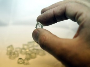 A natural diamond is held by a technician during the cutting process at the Kristall Production Corp. factory in Smolensk, Russia, on Friday, Dec. 2, 2011.