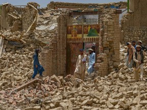 Villagers along with rescue workers examine the extent of damage at a village following an earthquake in Bernal district, Paktika province, on June 23, 2022.