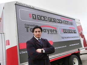 Franco Terrazzano, federal director with the Canadian Taxpayers Federation poses in front of the organization’s Debt Clock on Wednesday, April 20, 2022 during a stop in Windsor.