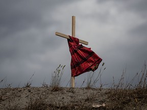 A girl's dress hung on a cross blows in the wind near the former Kamloops Indian Residential School in a file photo from June 4, 2021.
