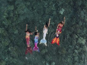 Queen Pangke Tabora, right, swims with her students during a mermaiding class.