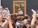 Visitors take photos of the Mona Lisa at the Louvre Museum after a man smeared cake on the masterpiece's protective glass in a protest about climate change, on May 29, 2022, in Paris.