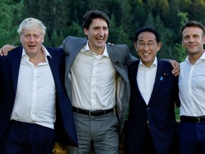 British Prime Minister Boris Johnson, Canadian Prime Minister Justin Trudeau, Japanese Prime Minister Fumio Kishida and French President Emmanuel Macron pose for a photograph next to a bench where Germany's then-Chancellor Angela Merkel and U.S. then-President Barack Obama were photographed during a G7 summit in 2015, during the first day of the G7 leaders' summit at Bavaria's Schloss Elmau castle, near Garmisch-Partenkirchen, Germany, June 26, 2022.