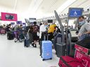 People wait in line to check in at Pearson International Airport in Toronto on May 12, 2022.