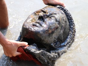 A kayaker fishes the head of a statue of Queen Victoria from the Assiniboine River in Winnipeg, Friday, July 2, 2021. Her statue and a statue of Queen Elizabeth II were toppled and vandalized on Canada Day.