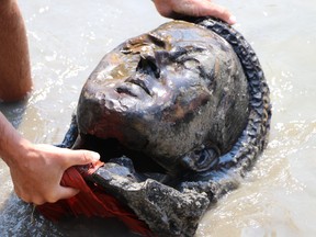 Ein Kajakfahrer fischt am Freitag, den 2. Juli 2021, den Kopf einer Statue von Königin Victoria aus dem Assiniboine River in Winnipeg. Ihre Statue und eine Statue von Königin Elizabeth II. wurden am Canada Day gestürzt und zerstört.