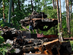 Ukrainian servicemen collect destroyed Russian tanks outside the village of Dmytrivka, in Kyiv region, on June 20, 2022 amid the Russian invasion of Ukraine.