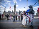 Assorted protesters and rally-goers stand on Wellington Street in front of the Parliament buildings in Ottawa, March 6, 2022.