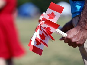 A volunteer holds souvenir flags to be distributed at a Winnipeg park on July 1, 2019.