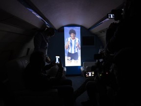 Journalists record a video inside a plane during a presentation of an aircraft dedicated to the late soccer legend Diego Maradona, at a military base in Moron, on the outskirts of Buenos Aires, Argentina, Wednesday, May 25, 2022. A ceremony was held before the airplane departs for different provinces of Argentina and other parts of the world reaching its final destination at the World Cup in Qatar at the end of the year. The aircraft, owned by a local business group, will carry and display jerseys and other objects that belonged to Maradona. It is one of the many tributes planned to coincide with the first World Cup since his death.