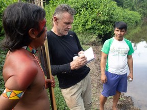 Veteran foreign correspondent Dom Phillips (C) talks to two indigenous men in Aldeia Maloca Papi?, Roraima State, Brazil, on Nov. 16, 2019.