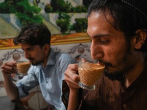 Men drink a cup of tea at a restaurant in Islamabad on June 15.