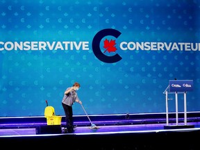 A woman cleans the stage at Conservative leader Erin O'Toole's election night headquarters during the Canadian federal election in Oshawa, Ont., on September 20, 2021. The Conservatives have confirmed about 675,000 members signed up to vote for a new leader, a staggering number that the Tories believe sets an all-time record for any federal political party.