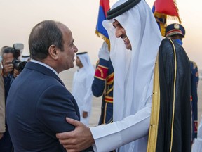 In this photo made available by Qatar News Agency, QNA, Qatari Emir Tamim bin Hamad Al Thani, right, is welcomed by Egyptian President Abdel-Fattah el-Sissi upon his arrival at Cairo airport, in Cairo, Egypt, Friday, June 24, 2022. Qatar's emir arrived to hold talks with Egypt's president in his first visit since the two countries agreed to reset relations after more than seven years of diplomatic animosity. (QNA via AP)